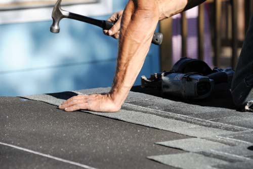 team member installing shingles on roof