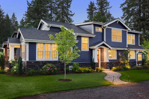 blue siding home with lights on at dusk