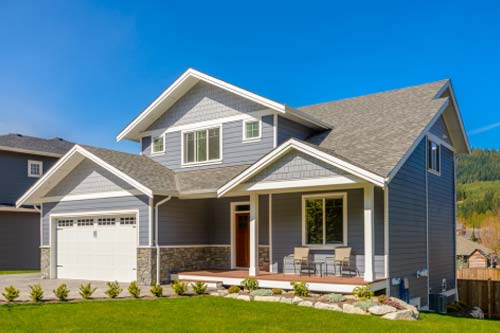Gray siding home with green grass lawn.