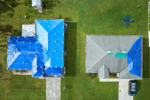 Aerial view of home roof with blue tarp for roof replacement